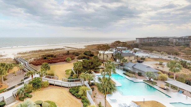 Um resort com piscina, vista para a praia e área de estacionamento.