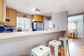A kitchen with a countertop, a refrigerator, cabinets, and a window with blinds. - Updated coastal villa with pools, athletic courts, gym, smart TVs, AC, & W D (Hilton Head)