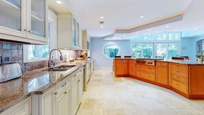 A spacious kitchen with granite countertops, wooden cabinets, and a large island. - Spacious, Renovated House with Private Spa and Private Pool (Hilton Head)