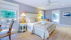 A bedroom with a bed, bedside lamps, a ceiling fan, and large windows. - Spacious, Renovated House with Private Spa and Private Pool (Hilton Head)