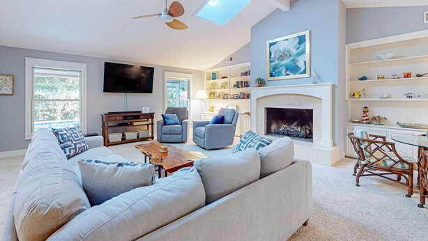 A living room with a sofa, armchairs, a fireplace, a television, and a bookshelf. - Spacious, Renovated House with Private Spa and Private Pool (Hilton Head)