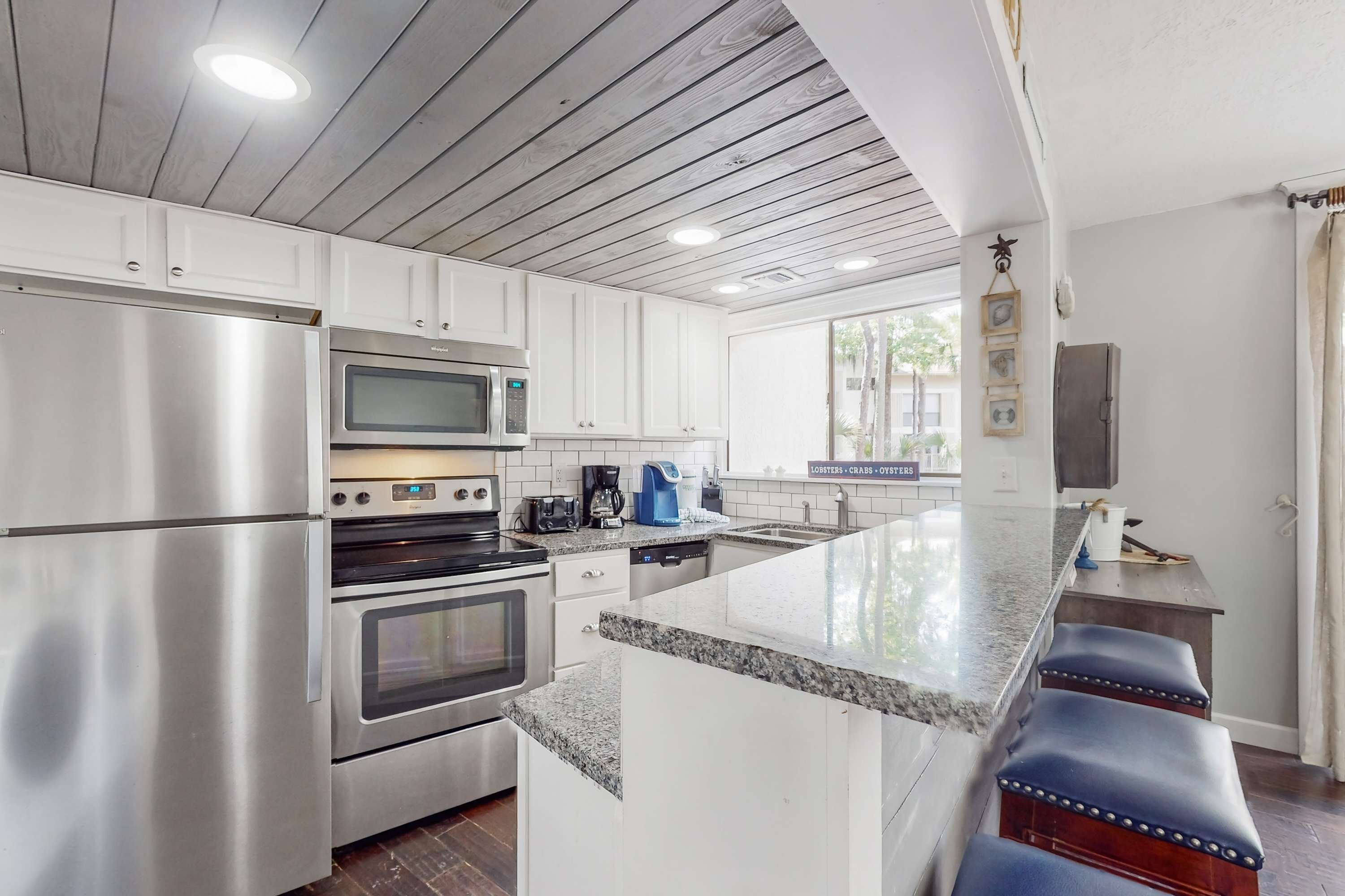 A modern kitchen with stainless steel appliances, a granite countertop, and a bar area with stools.