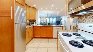 Una cocina moderna con armarios de madera, un refrigerador de acero inoxidable, horno empotrado y encimera de granito.