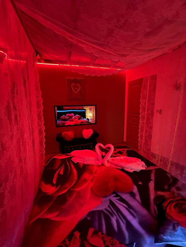 A room with a bed, a television, and a heart-shaped decoration on the wall.