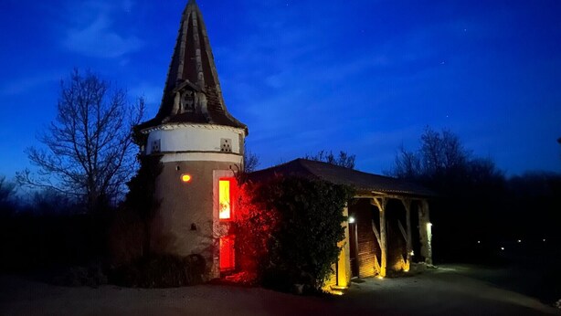 A church with a tall steeple, a lit entrance, and a covered porch. - Lz Secret du Pigeonnier: The Jewel of Your Desires (Lavaurette)