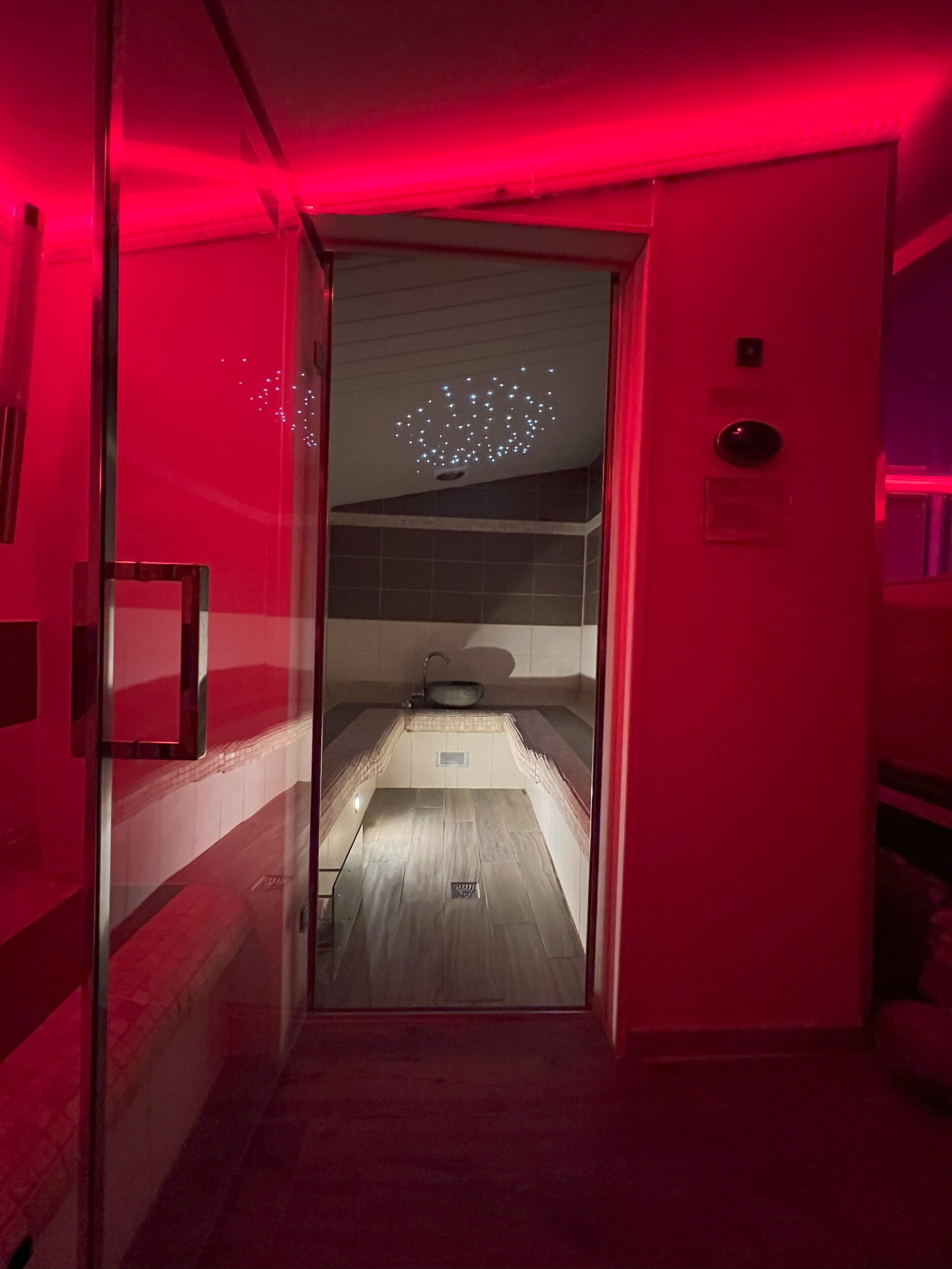 Una habitación con techo iluminado en rojo, un lavamanos y un espejo en la pared.