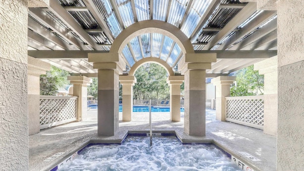 Uma área de hidromassagem com vista para uma piscina e árvores.
