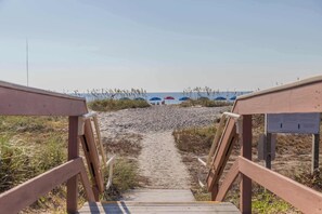 A wooden pathway leading to beach umbrellas. - Charming Waterfront Getaway with Seasonal Pool & Hot Tub, Tennis, Beach Access (Hilton Head)