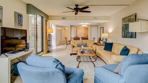 A spacious living room with a ceiling fan, a sofa set, a coffee table, and a television. - Resort Condo with Al Fresco Dining, Shared Pool, Hot Tub & Beach Access (Hilton Head)