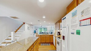 Eine Küche mit Holzausstattung, Granit Arbeitsplatten, einem weißen Kühlschrank und einem Essbereich mit Blick.