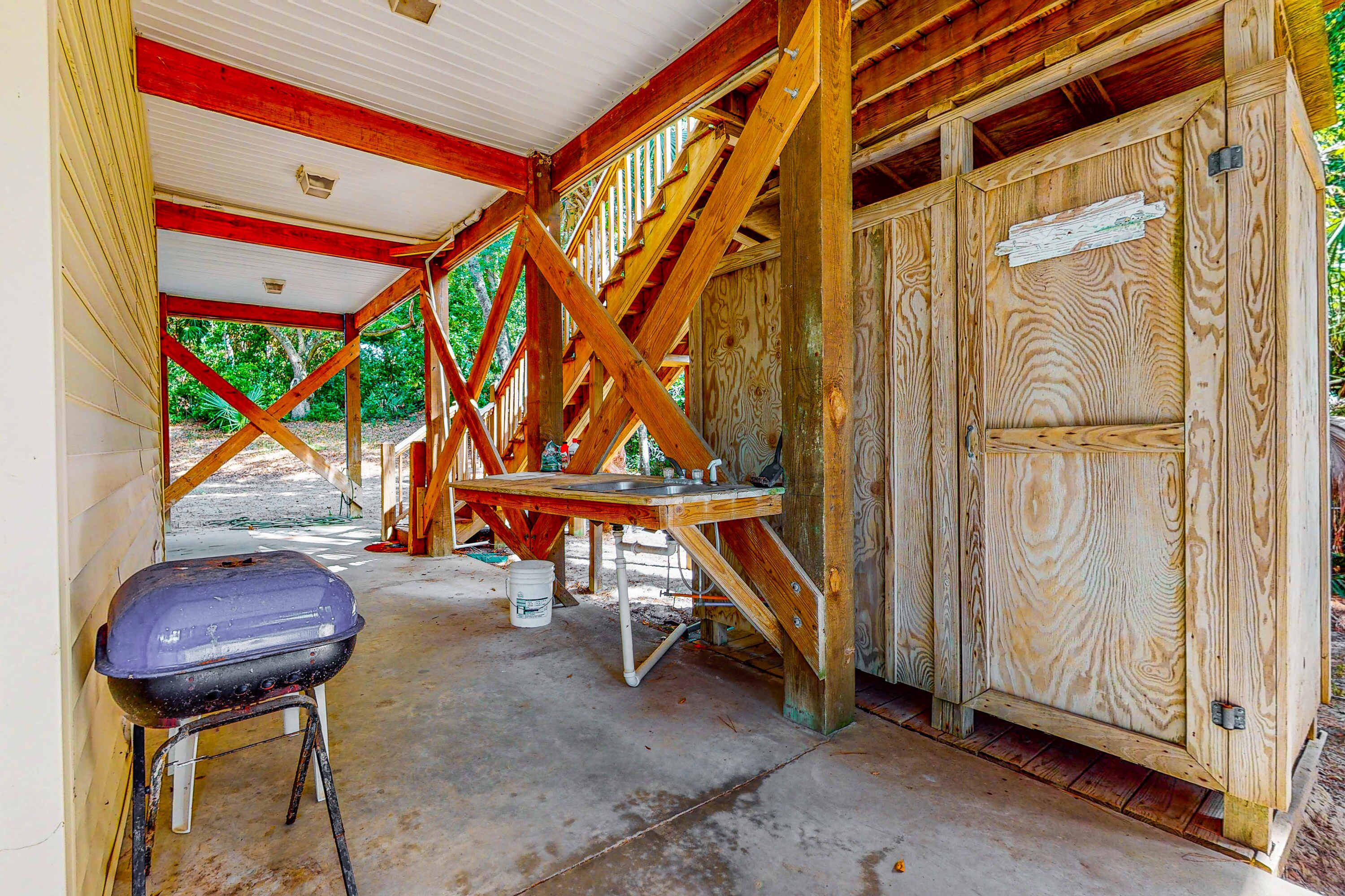 Un espace extérieur abrité, doté d’une structure en bois, d’une table et d’un barbecue.