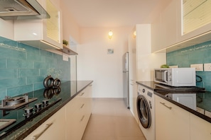 Cocina compacta con estufa, microondas y lavadora.