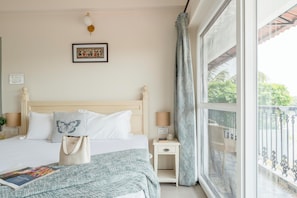 A neatly arranged bedroom with a bed, bedside tables, a window with a view, and a wall-mounted lamp. - Staymaster Agua De Marra 1 (Marra)