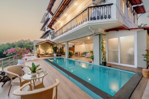 A swimming pool with a glass edge, wicker furniture, and potted plants. - Staymaster Agua De Marra 1 (Marra)