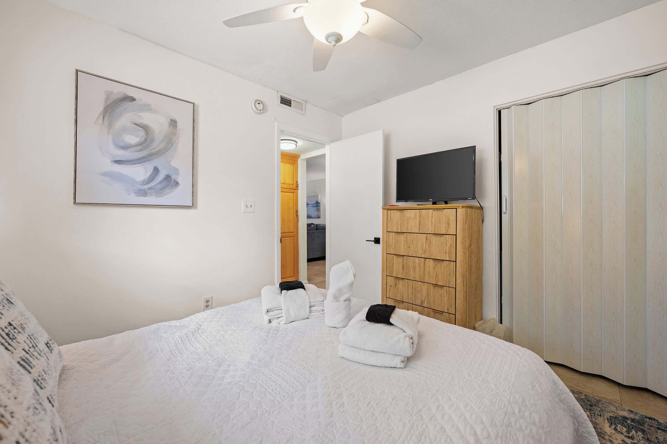 Ein Schlafzimmer mit einem Bett, einem Fernseher, einem Kleiderschrank und einem Bild an der Wand.