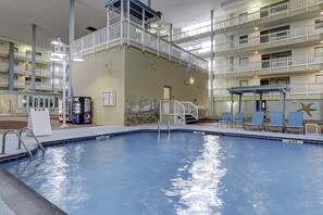 An indoor swimming pool with a multi-level balcony, lounge chairs, and a Pepsi vending machine. - Beach condo with balcony, pools, & hot tub- near golf & beach (Hilton Head)