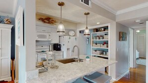 A kitchen with a marble countertop, stainless steel sink, and two pendant lights. - Palmetto Dunes condo with shared pool, private WD and beach access (Hilton Head)