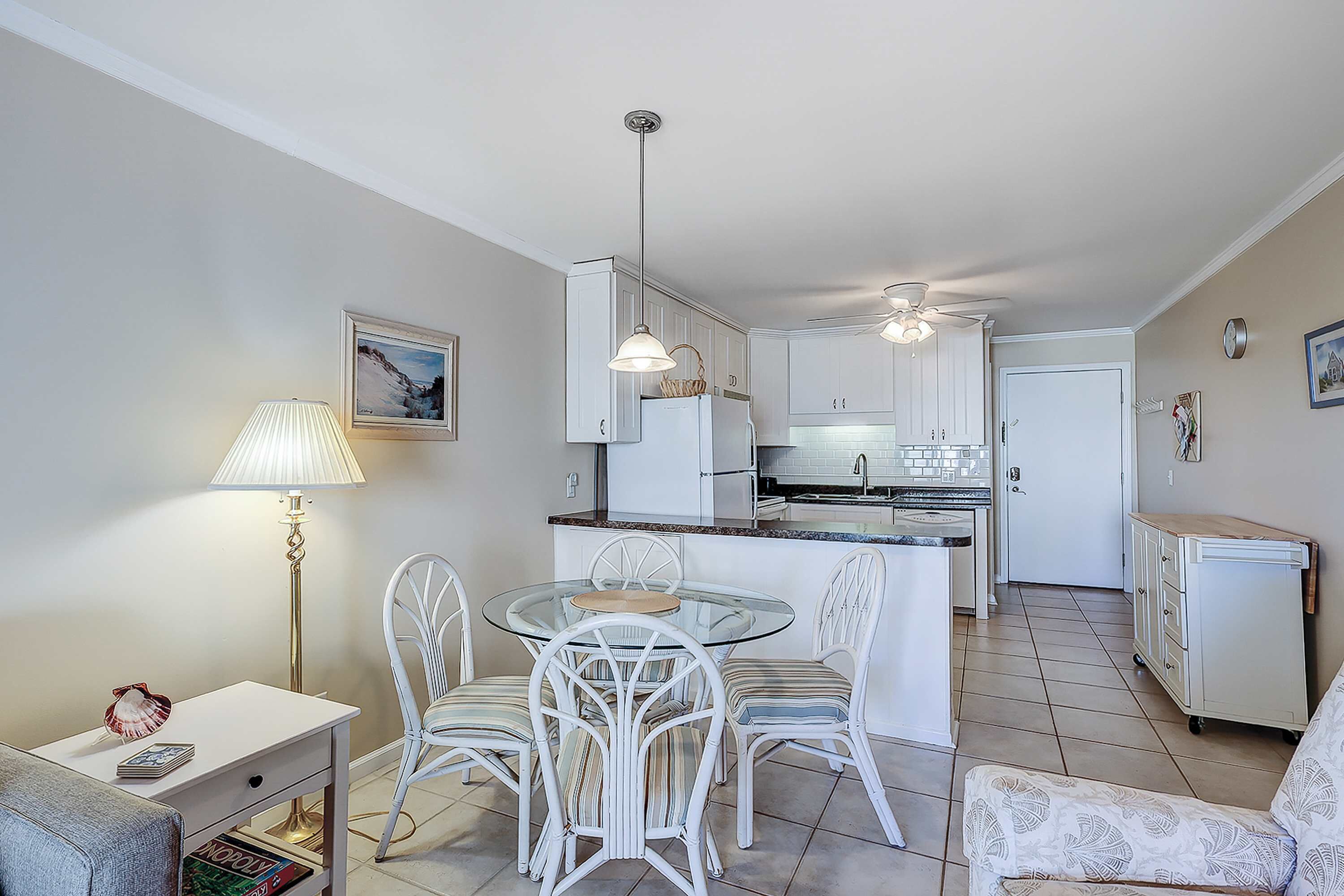 A modern kitchen with white cabinetry, a glass dining table, and a white chair.