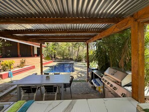 An outdoor patio with a pool, a barbecue grill, and a table with chairs. - Casa Avi Fauna | Nature • Pool • Beach 5m • 45 min LIR (Playa Ocotal, Sardinal)