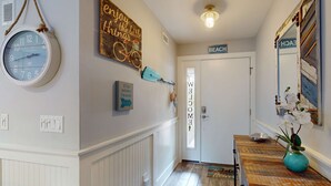 A hallway with a clock, a sign reading 'Enjoy the little things,' and a door labeled 'BEACH.' - Coastal condo- close to Coligny Plaza, Beach with shared pool (Hilton Head)