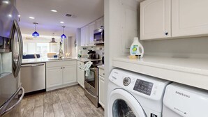 A modern kitchen with white cabinets, stainless steel appliances, and a Samsung washing machine. - Coastal condo- close to Coligny Plaza, Beach with shared pool (Hilton Head)