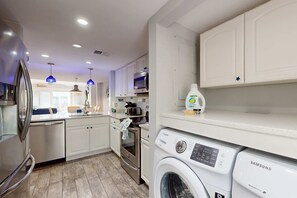 A modern kitchen with white cabinets, stainless steel appliances, and a Samsung washing machine. - Coastal condo- close to Coligny Plaza, Beach with shared pool (Hilton Head)