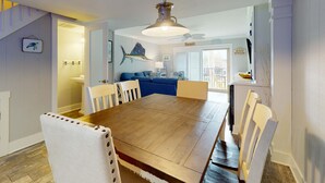 A dining area with a wooden table, white chairs, a ceiling fan, and a view of the living room. - Coastal condo- close to Coligny Plaza, Beach with shared pool (Hilton Head)