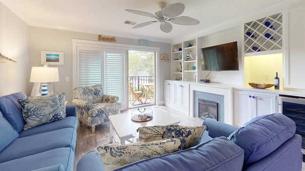 A living room with a sofa, armchair, and a coffee table. There is a television mounted on the wall and a fireplace. - Coastal condo- close to Coligny Plaza, Beach with shared pool (Hilton Head)