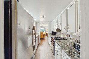 A kitchen with white cabinets, a granite countertop, a stove, and a microwave. - Pet friendly condo on golf course, near Tennis, Beach, Golfing & Coligny Plaza (Hilton Head)