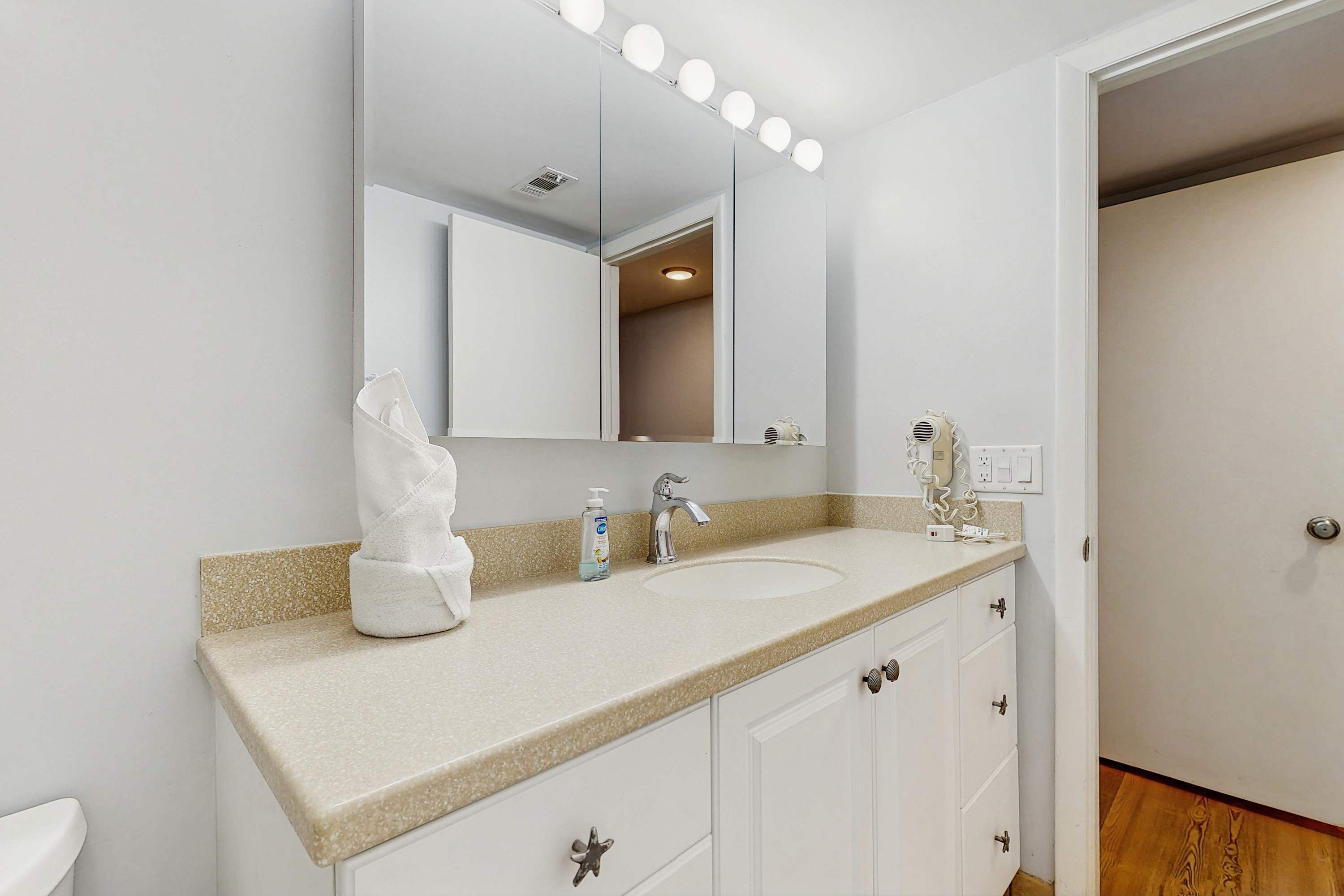 A bathroom with a sink, mirror, and vanity.