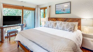 Ein Schlafzimmer mit Bett, Fernseher, Schreibtisch und Balkon.