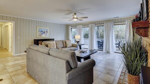 A living room with a sofa, a table, a lamp, and a ceiling fan. - Breezy resort home located in Sea Pines Resort near marina & restaurants (Hilton Head)