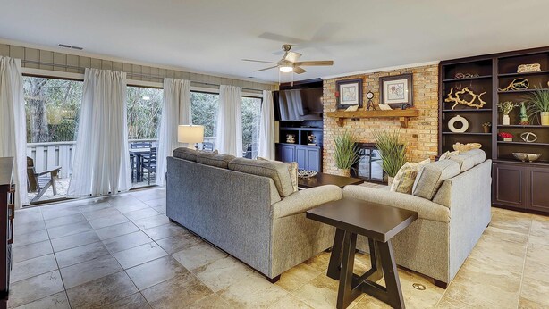 A living room with a sofa, a coffee table, a TV, and a fireplace. - Breezy resort home located in Sea Pines Resort near marina & restaurants (Hilton Head)