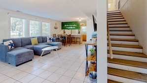 A living room with a sectional sofa, a dining table, and a staircase. - Spacious house by the beach with screened balcony & central AC (Hilton Head)