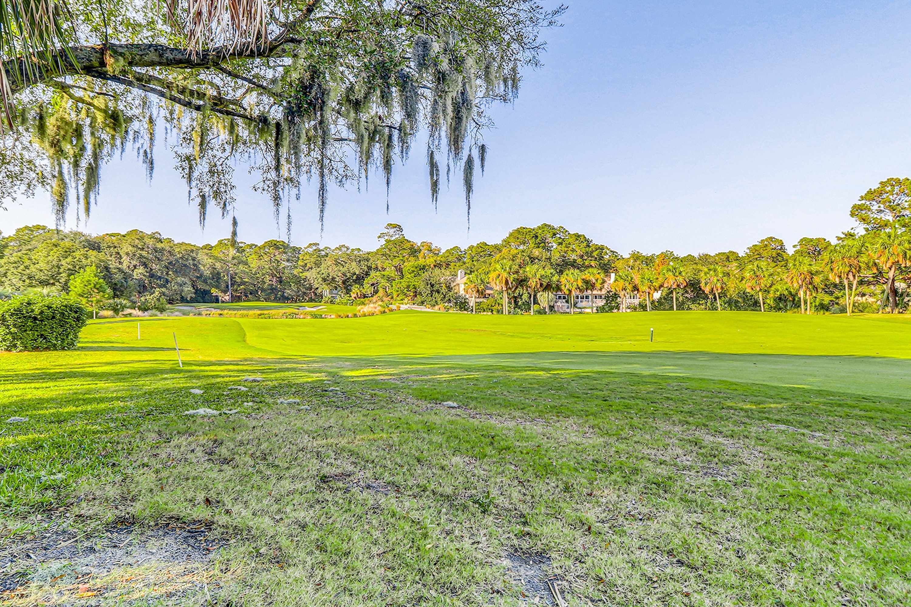 Un campo de golf con césped bien cuidado, un club de campo y árboles circundantes.