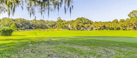 Un campo de golf con césped bien cuidado, un club de campo y árboles circundantes.