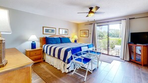 Une chambre à coucher comprenant un lit, des tables de chevet, un bureau, une chaise, un téléviseur et un balcon avec vue.
