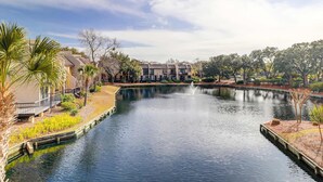 Una masa de agua tranquila con una fuente, rodeada de edificios y vegetación.
