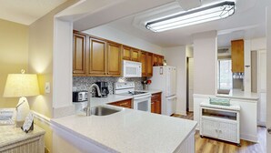 Una cocina moderna con armarios de madera, microondas, estufa y refrigerador.