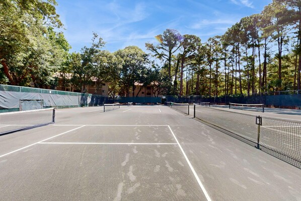 A tennis court with multiple courts, surrounded by trees and buildings. - Coastal Retreat with Patio, Shared Pools, Tennis & Playground - Walk to Beach (Hilton Head)