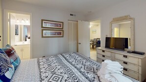 A bedroom with a bed, a dresser, a television, and a mirror. - Coastal Retreat with Patio, Shared Pools, Tennis & Playground - Walk to Beach (Hilton Head)