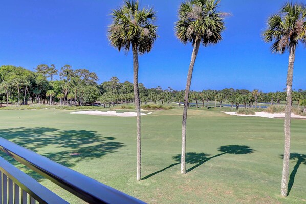 A golf course with palm trees, sand bunkers, and a clear blue sky. - Sea Pines condo with amazing golf course view, pool, & balcony - walk to beach (Hilton Head)