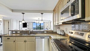 Una cucina moderna con lavastoviglie integrata, elettrodomestici in acciaio inossidabile, piani in granito e vista sull'esterno.