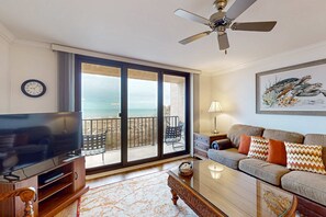 Ein Wohnzimmer mit Fernseher, einer Couch und einem Balkon mit Blick.