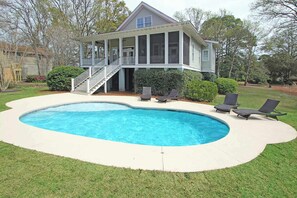 A house with a swimming pool, a covered porch, and a staircase leading to the entrance.