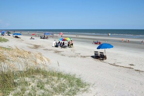 Ein Strand mit Sonnenschirmen, Liegestühlen und Personen.