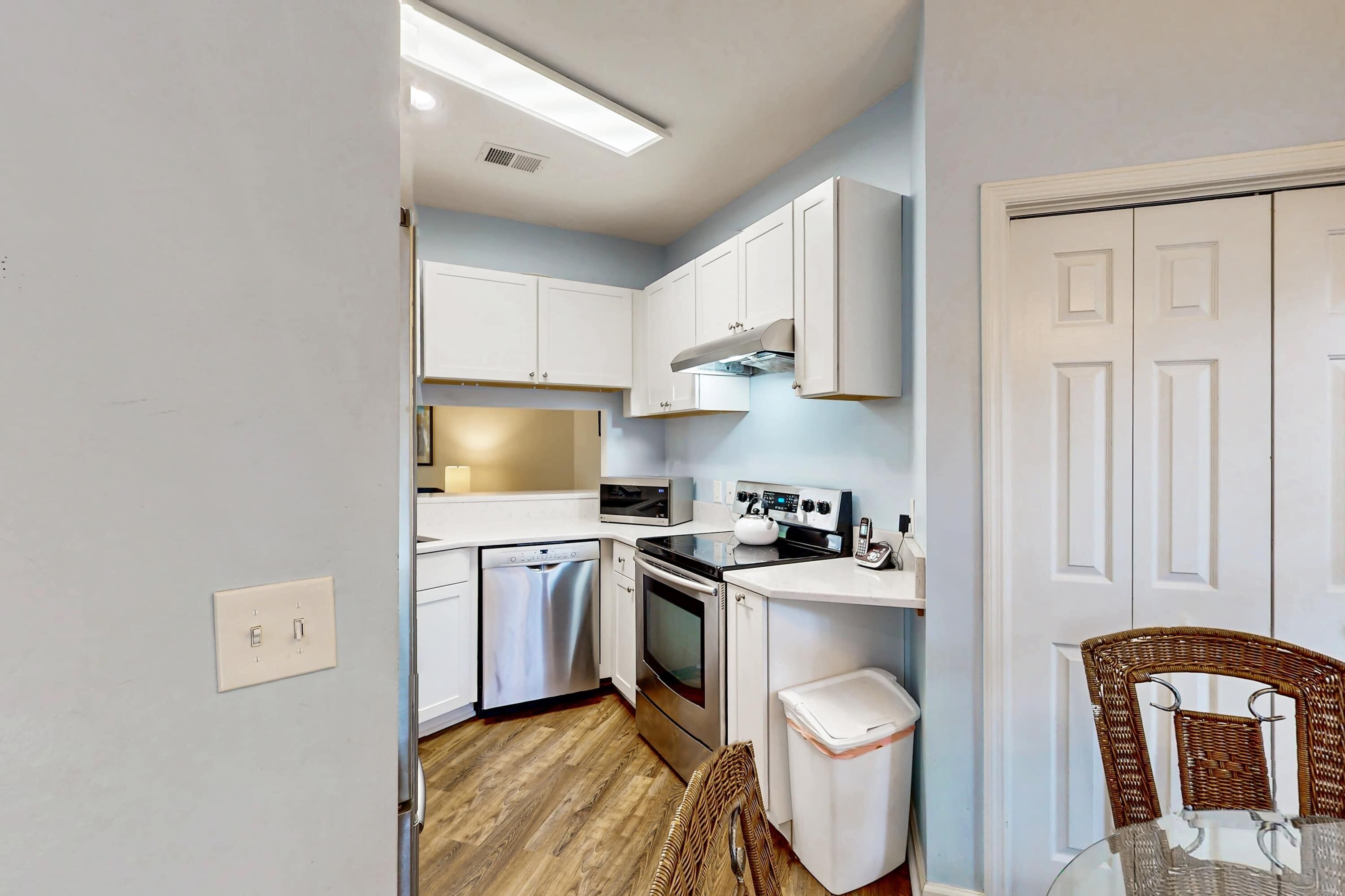 A compact kitchen with white cabinets, a microwave, a stove, and a dishwasher.