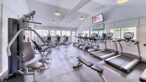 Une salle de sport équipée de tapis de course, d’appareils de musculation et de bancs d’exercices.