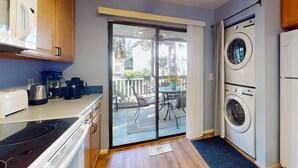 Una cocina equipada con microondas, cafetera y tostadora, un comedor con mesa y sillas, y un balcón con vistas al exterior.