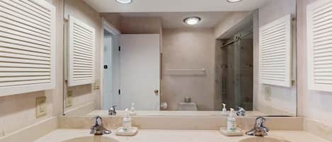 Un baño con dos lavamanos, un espejo grande y una ducha.